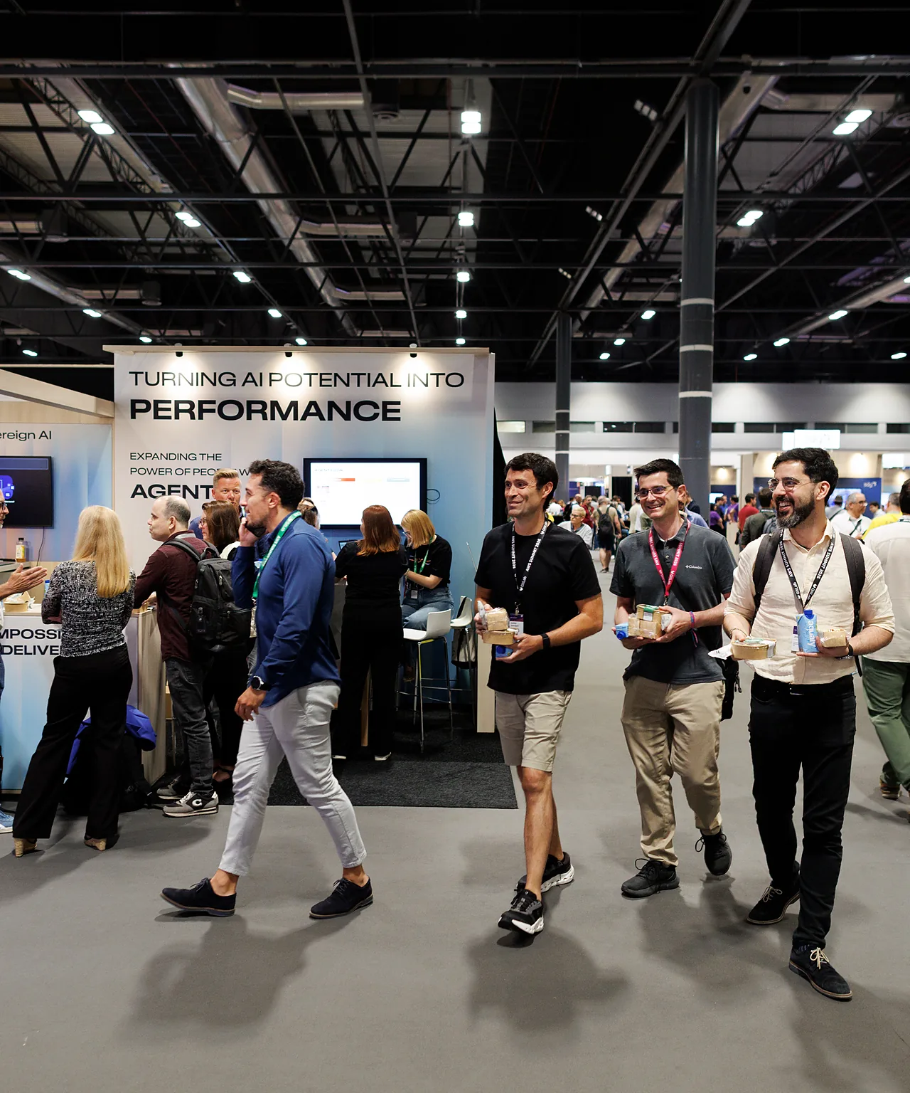 Visitors walking past the DXC stand on a busy exhibition floor