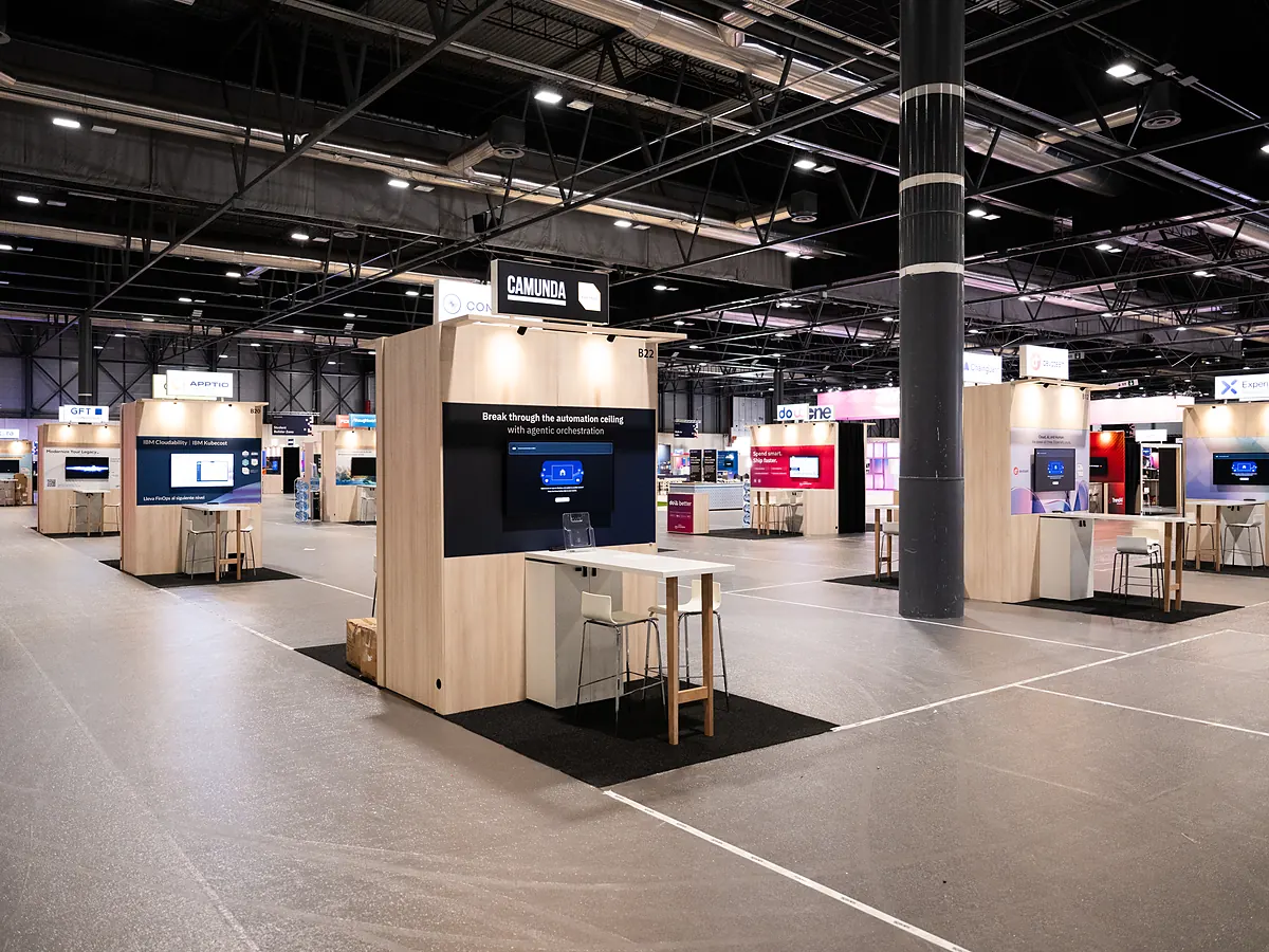 Caminda stand with a dark print wall, a screen and a high table with stools