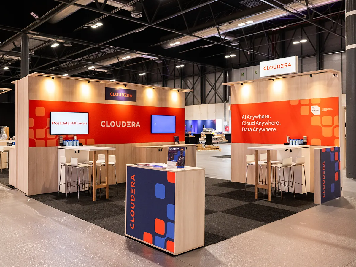 Cloudera stand with orange print walls, a screen and a counter with the logo