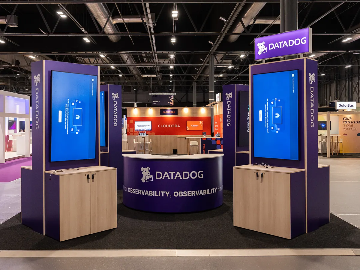 Datadog stand with two purple towers holding screens and a round counter with the logo