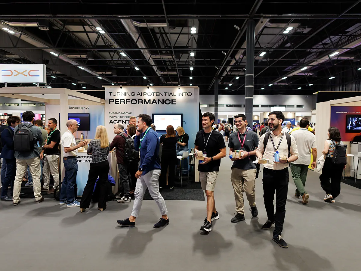 Visitors walking past the DXC stand on a busy exhibition floor