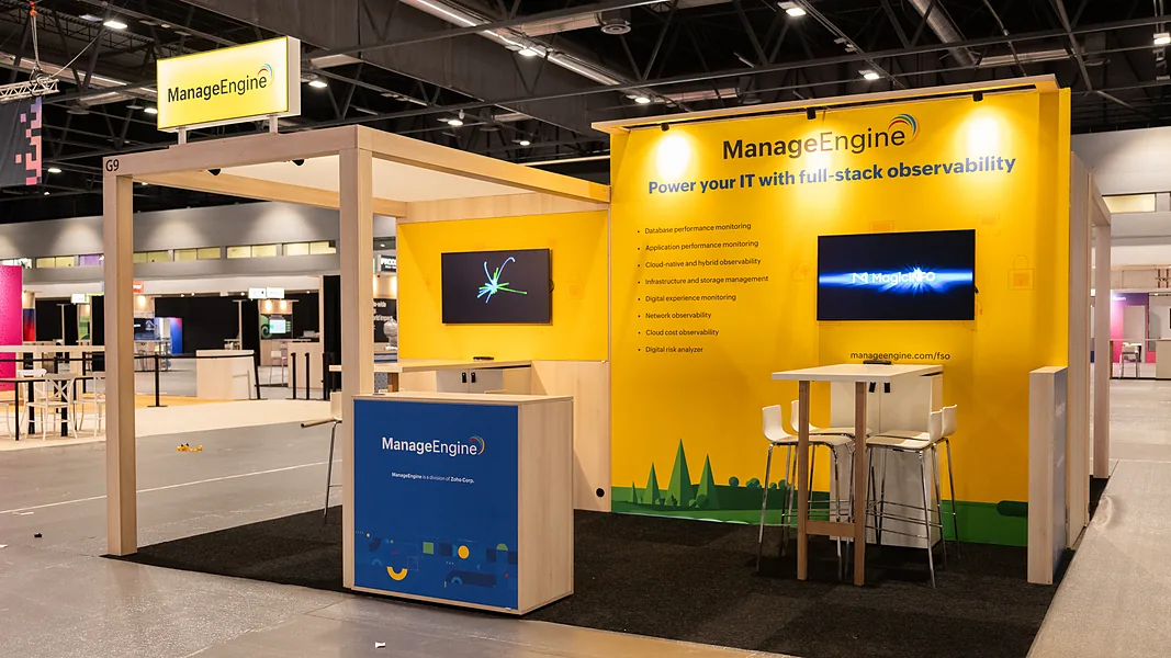 Stand van ManageEngine met een gele full color printwand, twee schermen en een balie met print